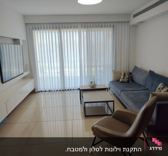 וילון לבן שקוף תלוי על חלון גדול בסלון